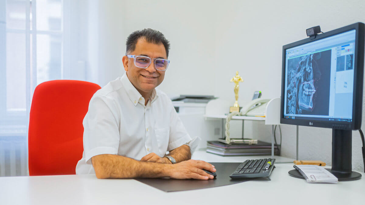 Dr. Ali Sohani sitz an seinem Schreibtisch in seiner kiefernorthopädischen Praxis in Heidelberg